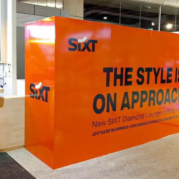photo de la palissade de chantier pour l'entreprise Sixt orange avec du texte noir ou il est écrit "the style is on approach" création par Signarama Montpellier