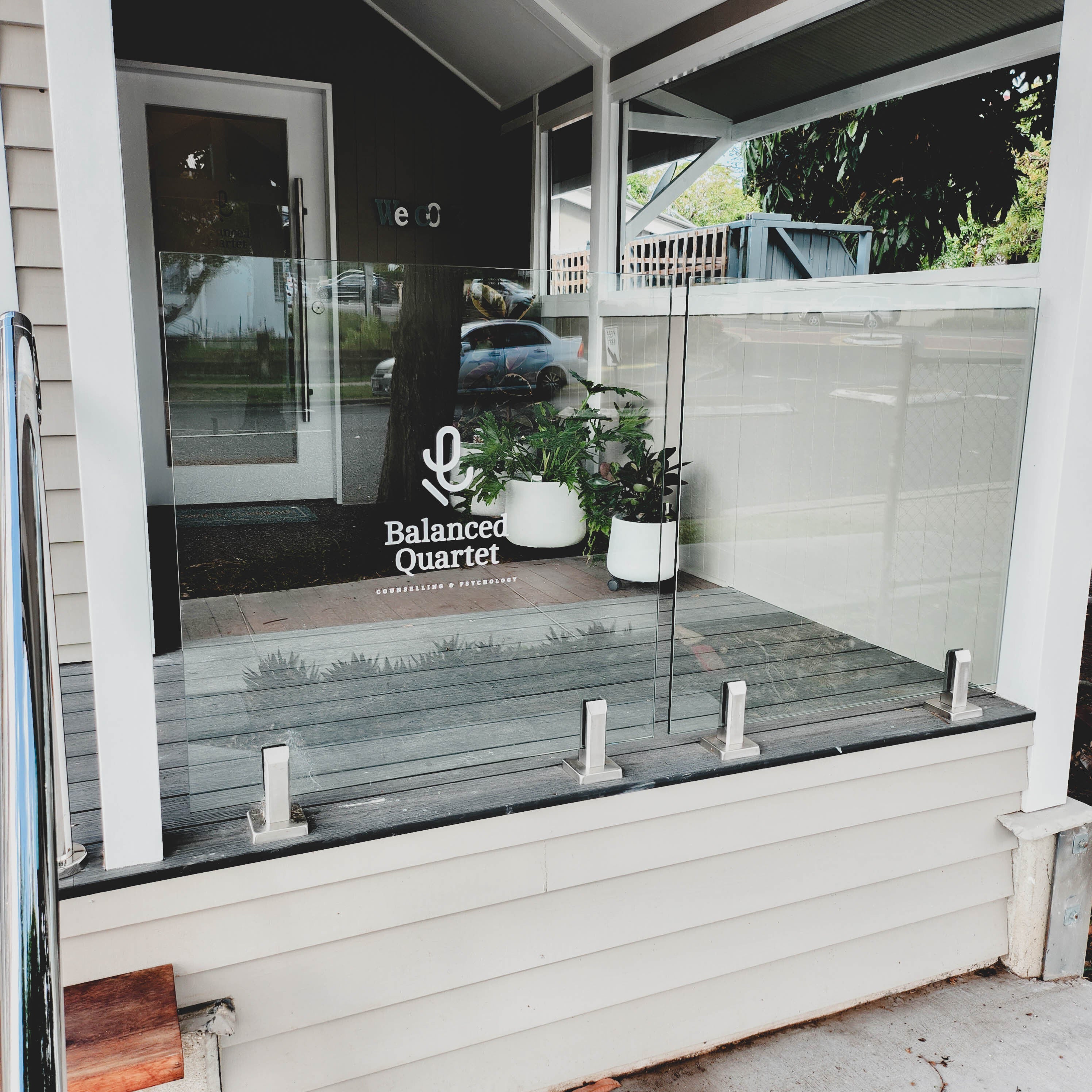White cut out vinyl decal attached to glass panel fencing