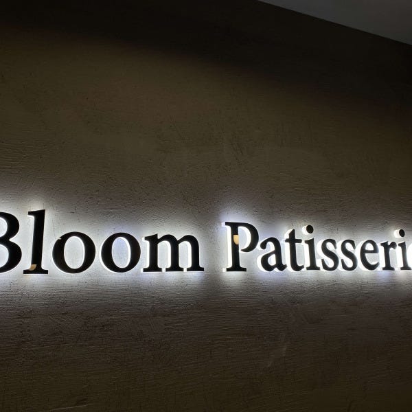 Illuminated 3D acrylic sign for Bloom Patisserie attached flush to wall.