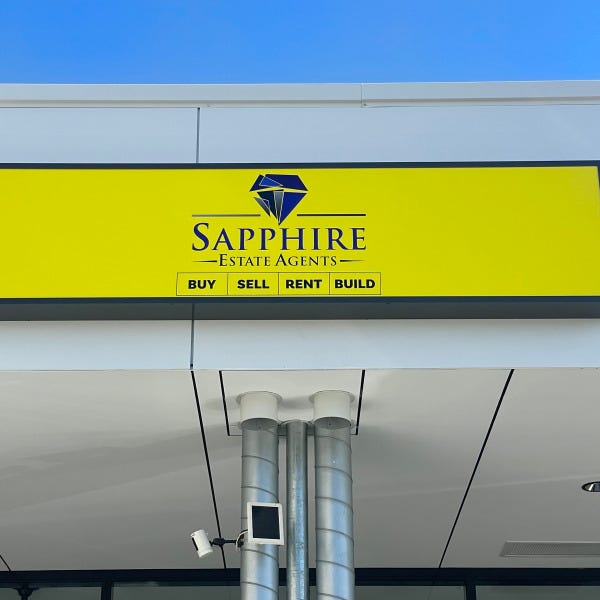 Illuminated lightbox signage featuring bright yellow and blue graphics for Sapphire Estate Agents by Signarama Brisbane CBD..