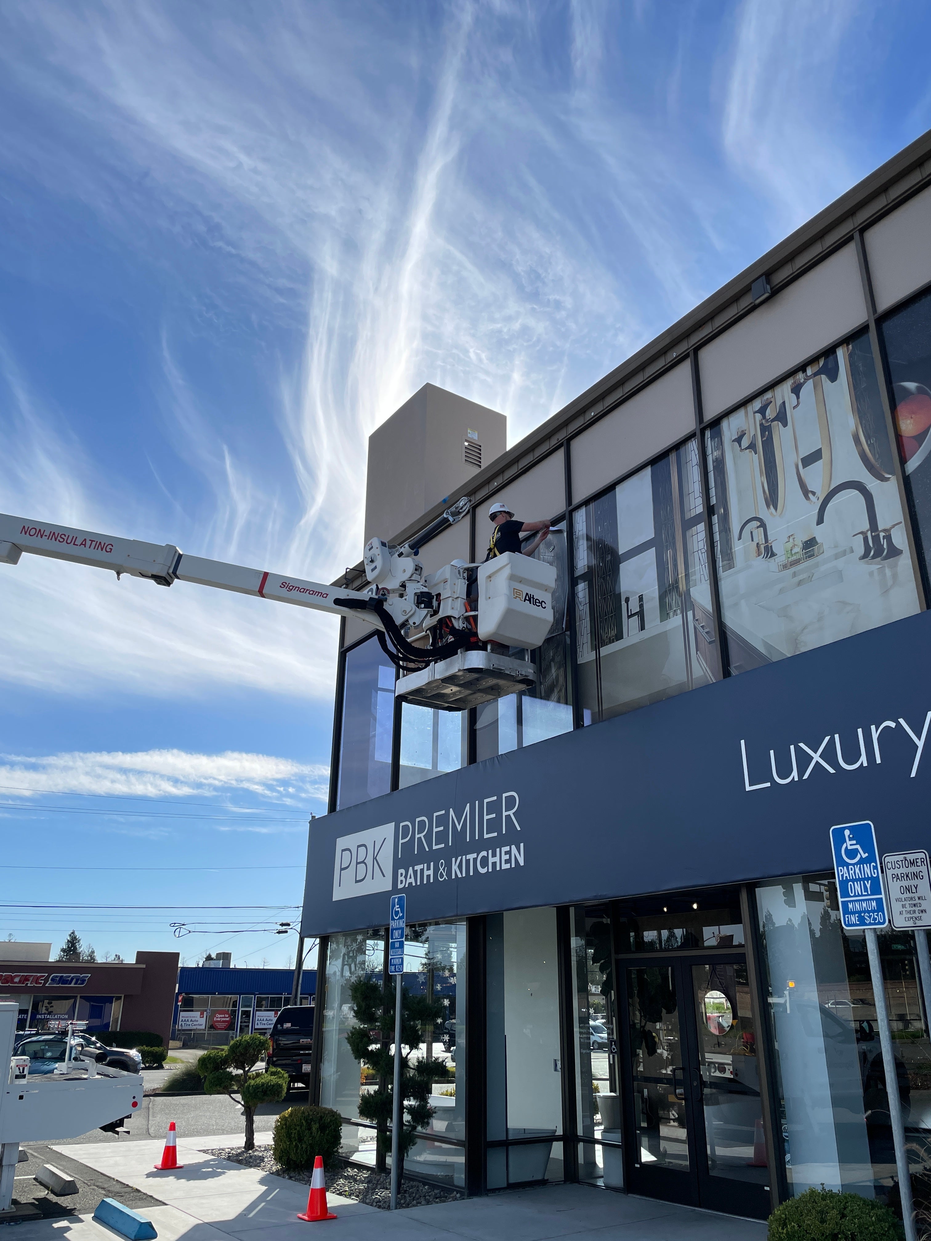 Bucket lift raised beside a commercial building during a sign installation