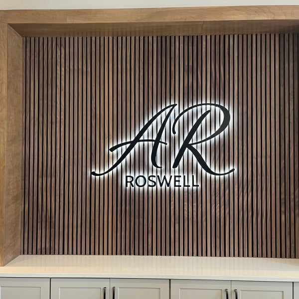 Illuminated AR Roswell logo on wood slat wall