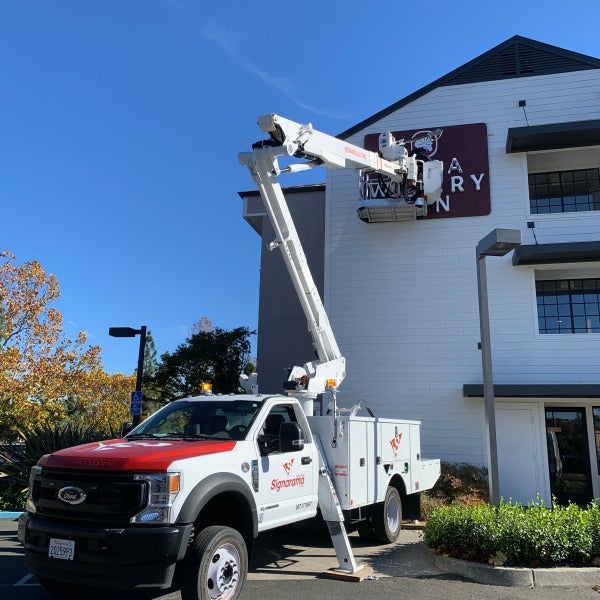Bucket truck installing channel letters on the Napa Winery Inn building
