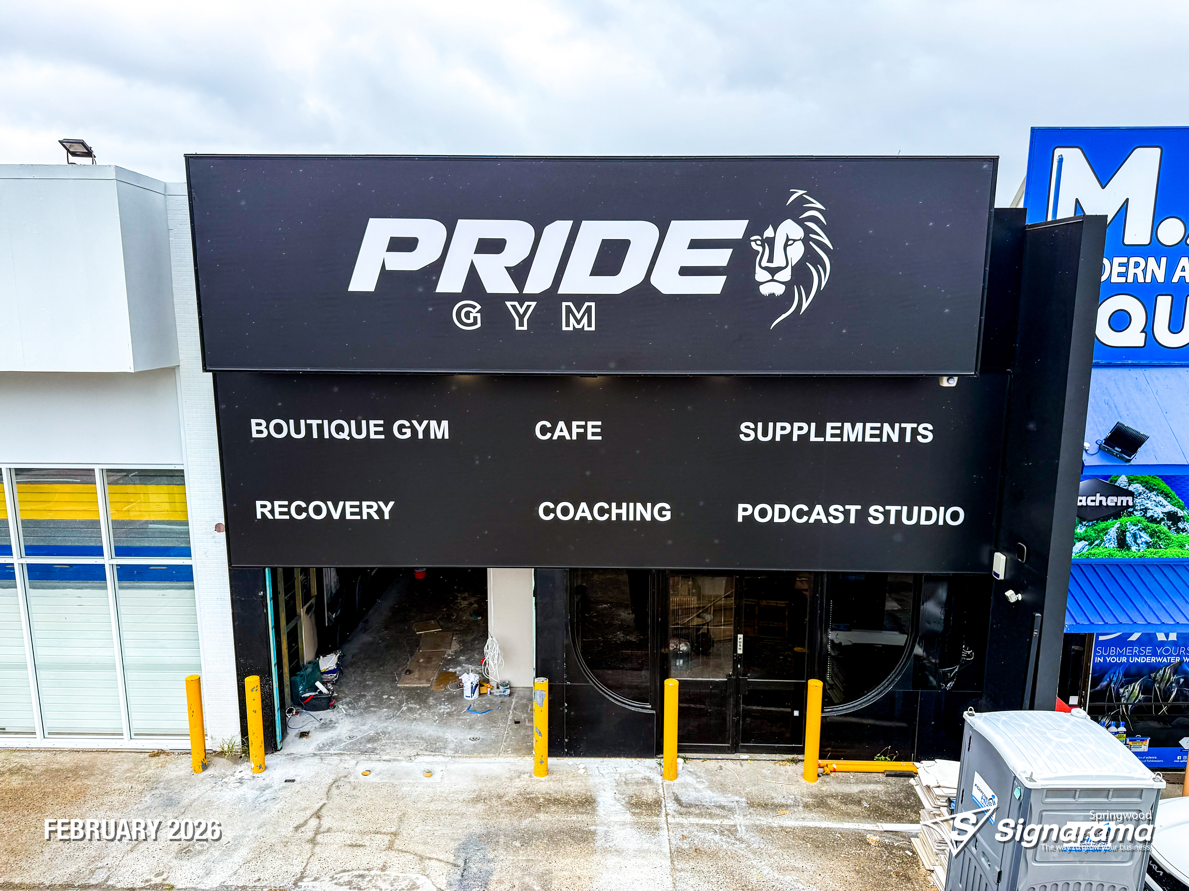 Large storefront sail track banners installed at Pride Gym by Signarama Springwood, featuring bold, high-impact graphics stretched tightly across the building façade to create stro...