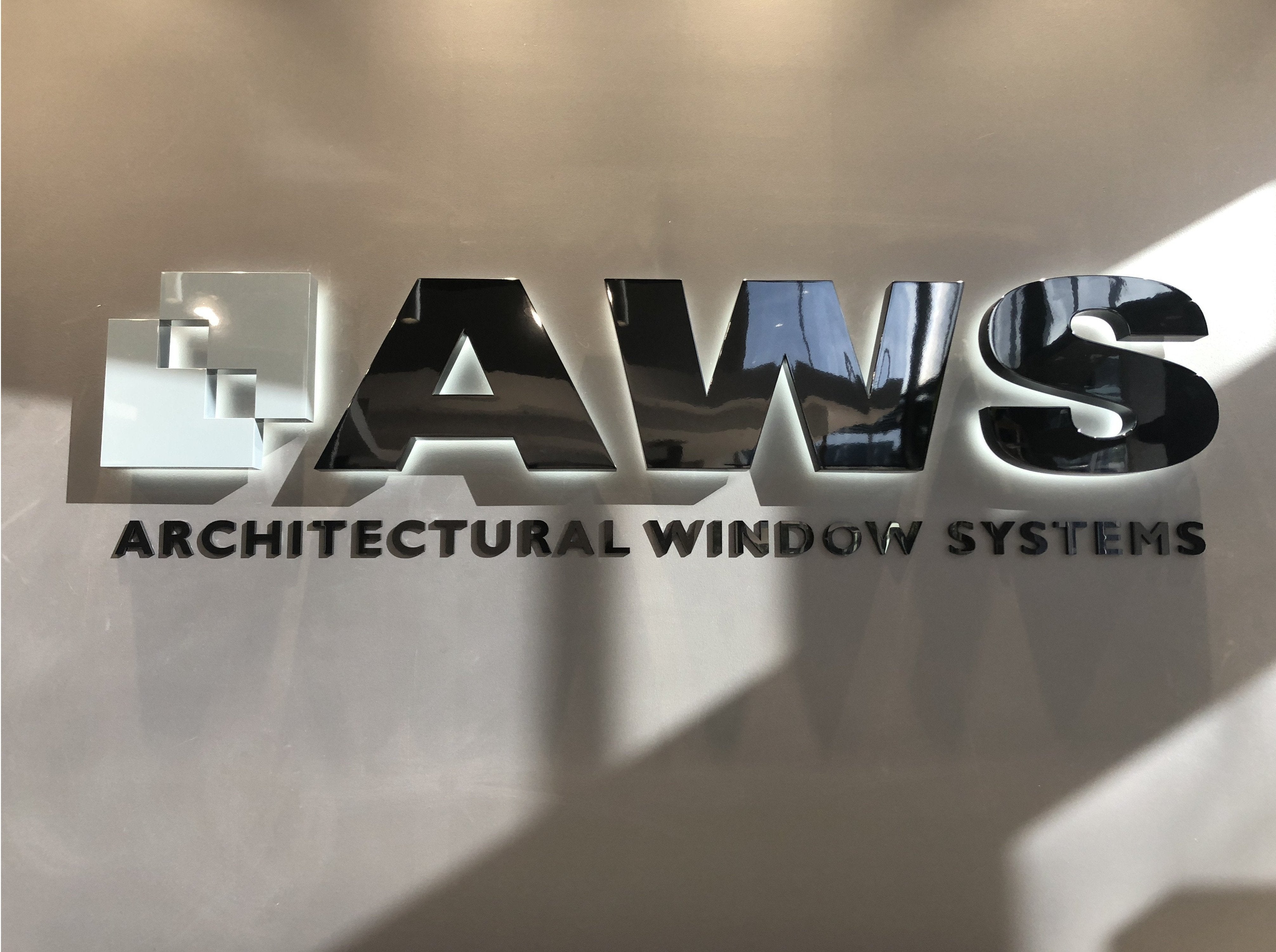 Stainless metal sign with chrome mirror finish | grey wall with halo lighting around letters. | Signarama