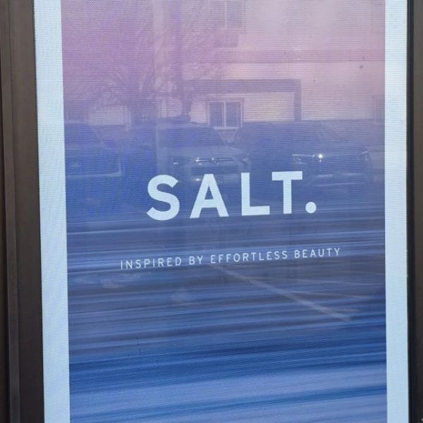 Perforated window graphics applied to storefront glass with one-way visibility