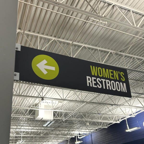 Women’s restroom wayfinding sign with directional icons