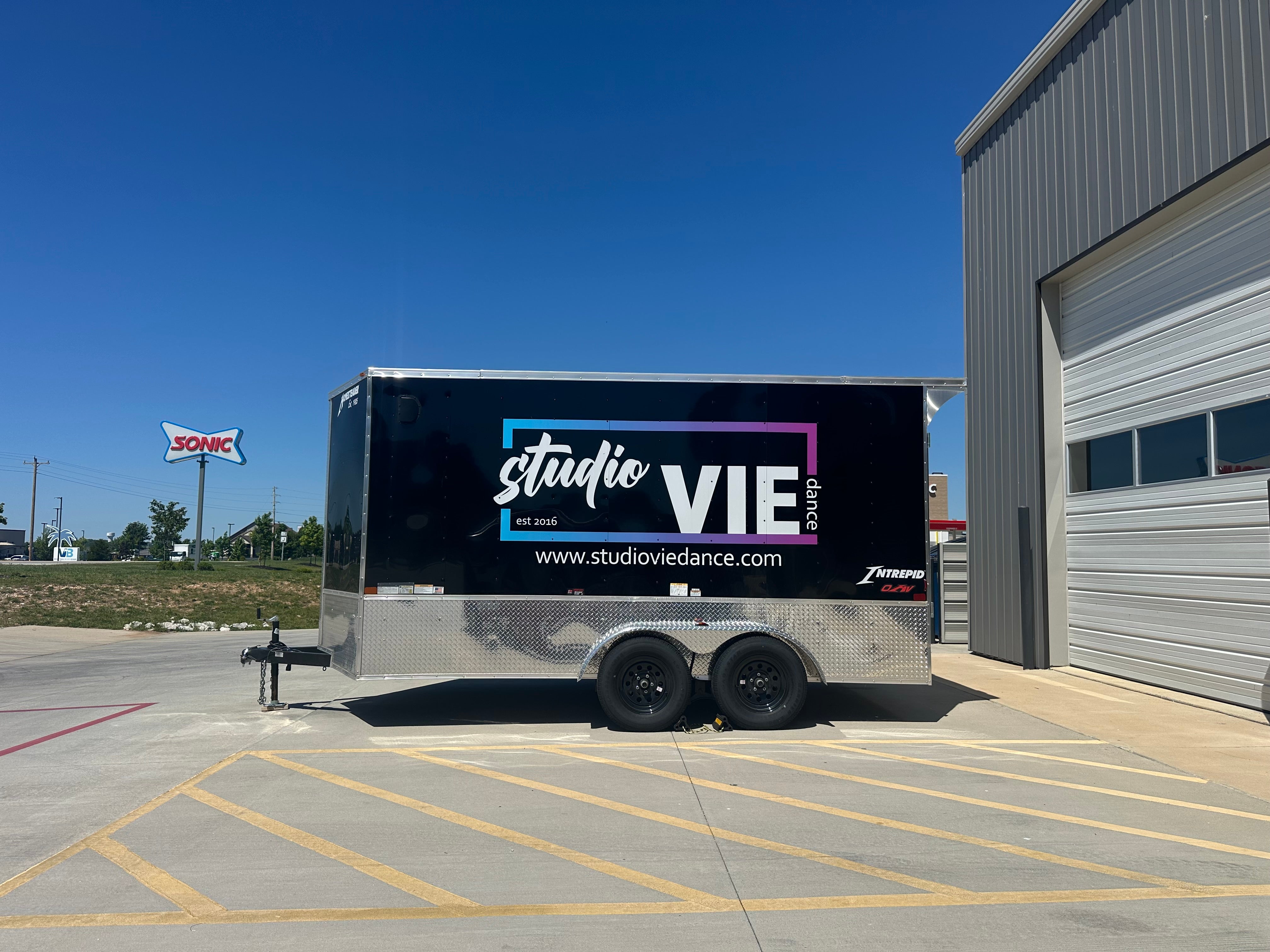 Professionally wrapped enclosed trailer featuring custom vinyl graphics for business promotion.