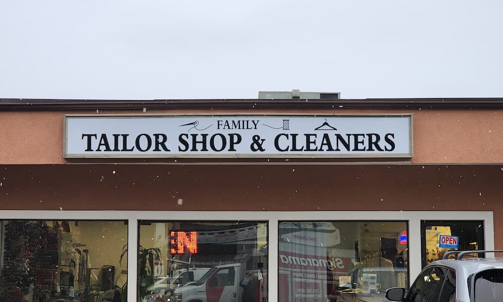 A rectangular storefront sign for Family Tailor Shop & Cleaners