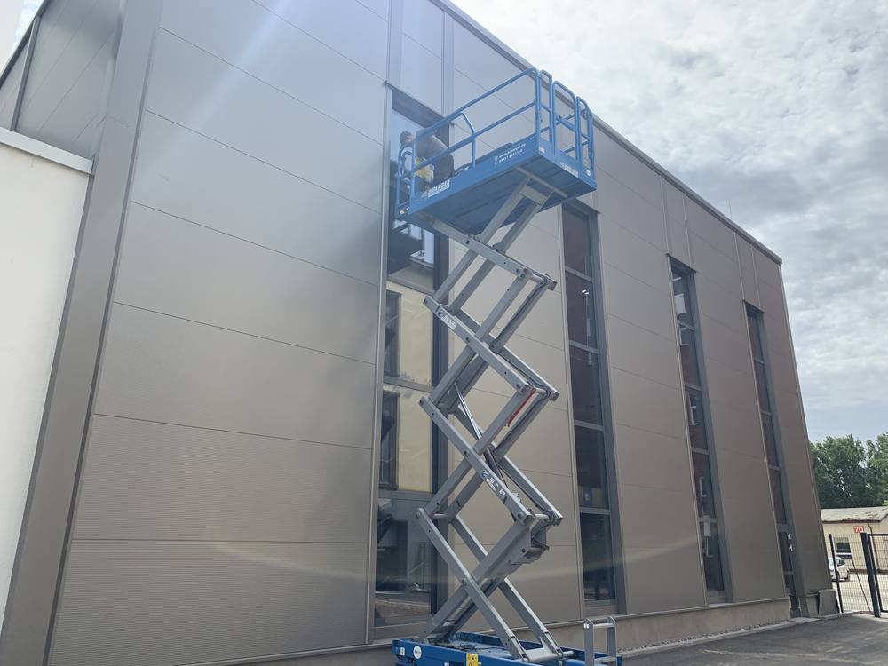 Folienmontage an einer Gewerbefassade per Hebebühne