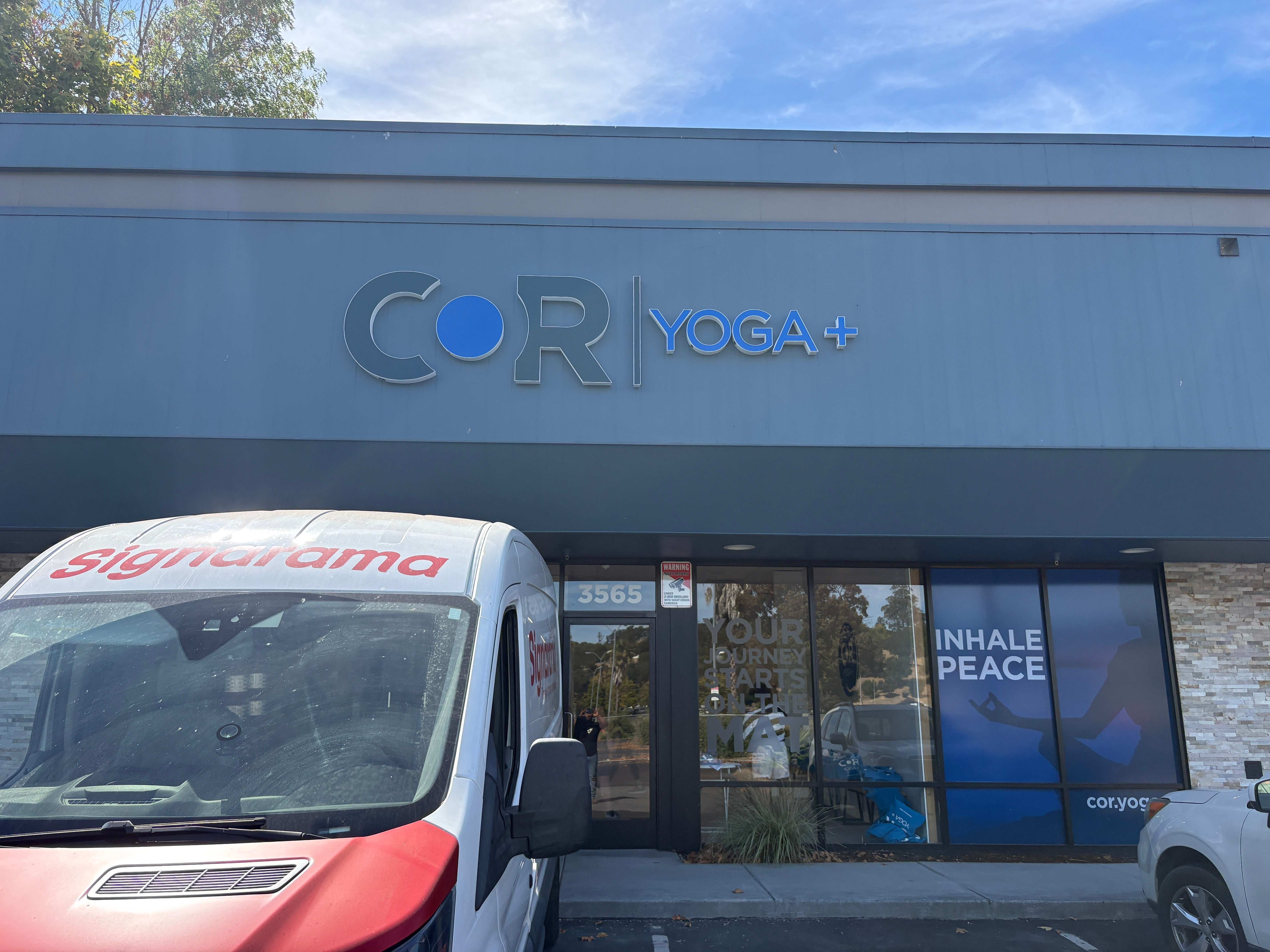 COR Yoga+ dimensional exterior logo above the storefront, with a Signarama installation van parked outside