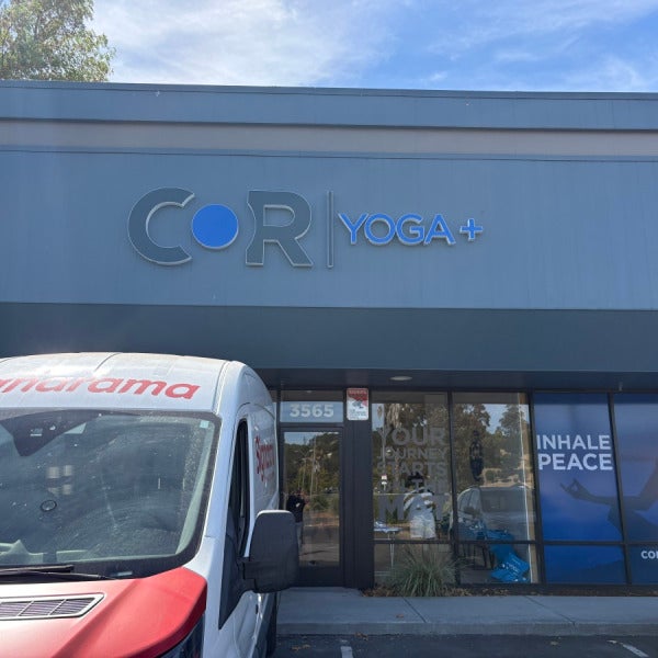COR Yoga+ dimensional exterior logo above the storefront, with a Signarama installation van parked outside