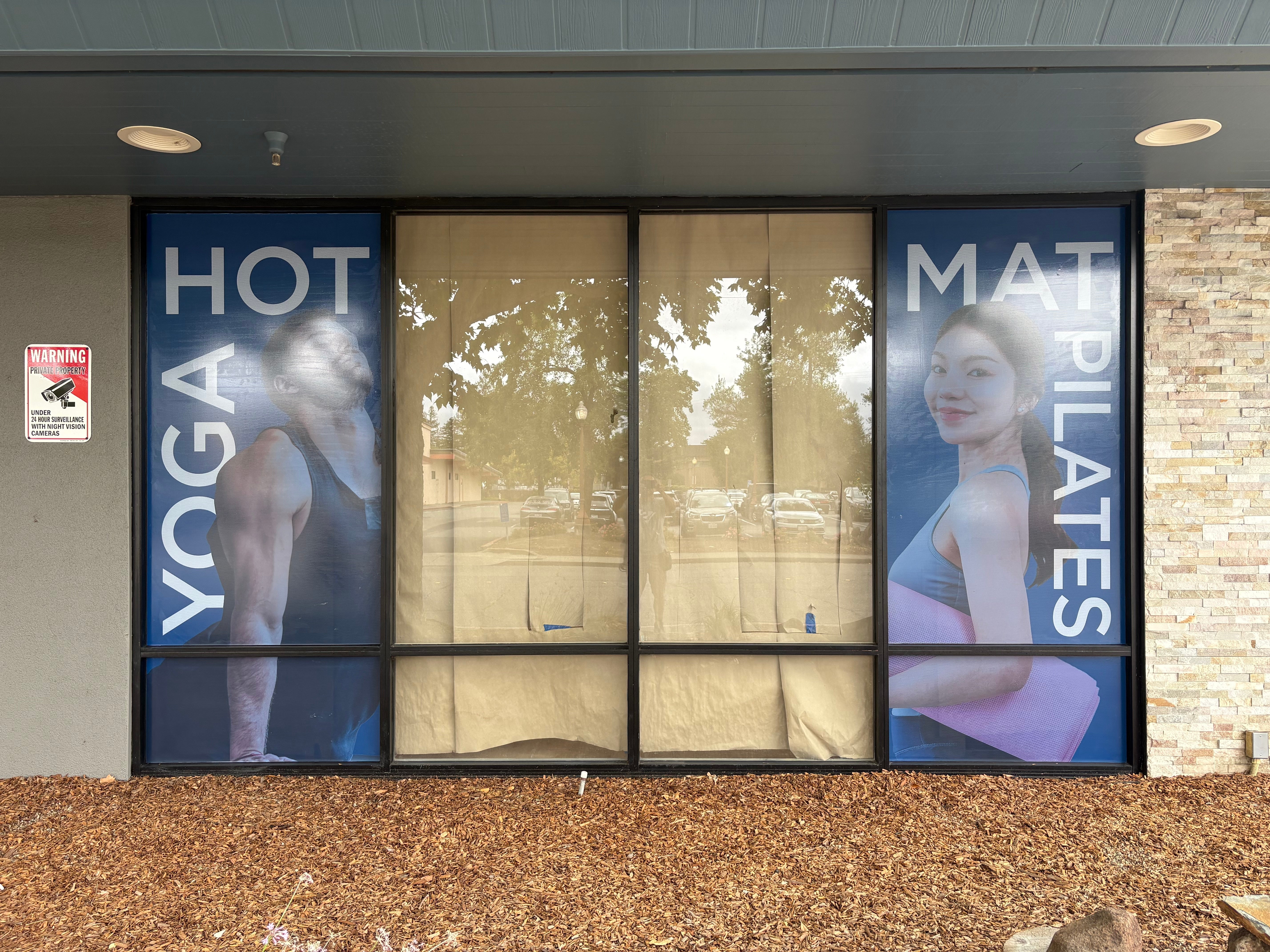 Tall COR Yoga+ window graphics showing Hot Yoga and Mat Pilates photography and white lettering