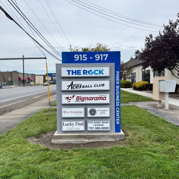 New blue-and-gray Piner Business Center monument with 915–917 address numbers, tenant logos and leasing information