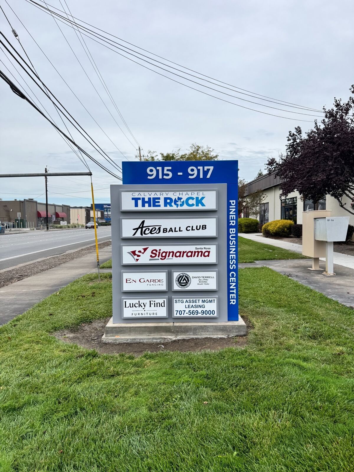 New blue-and-gray Piner Business Center monument with 915–917 address numbers, tenant logos and leasing information