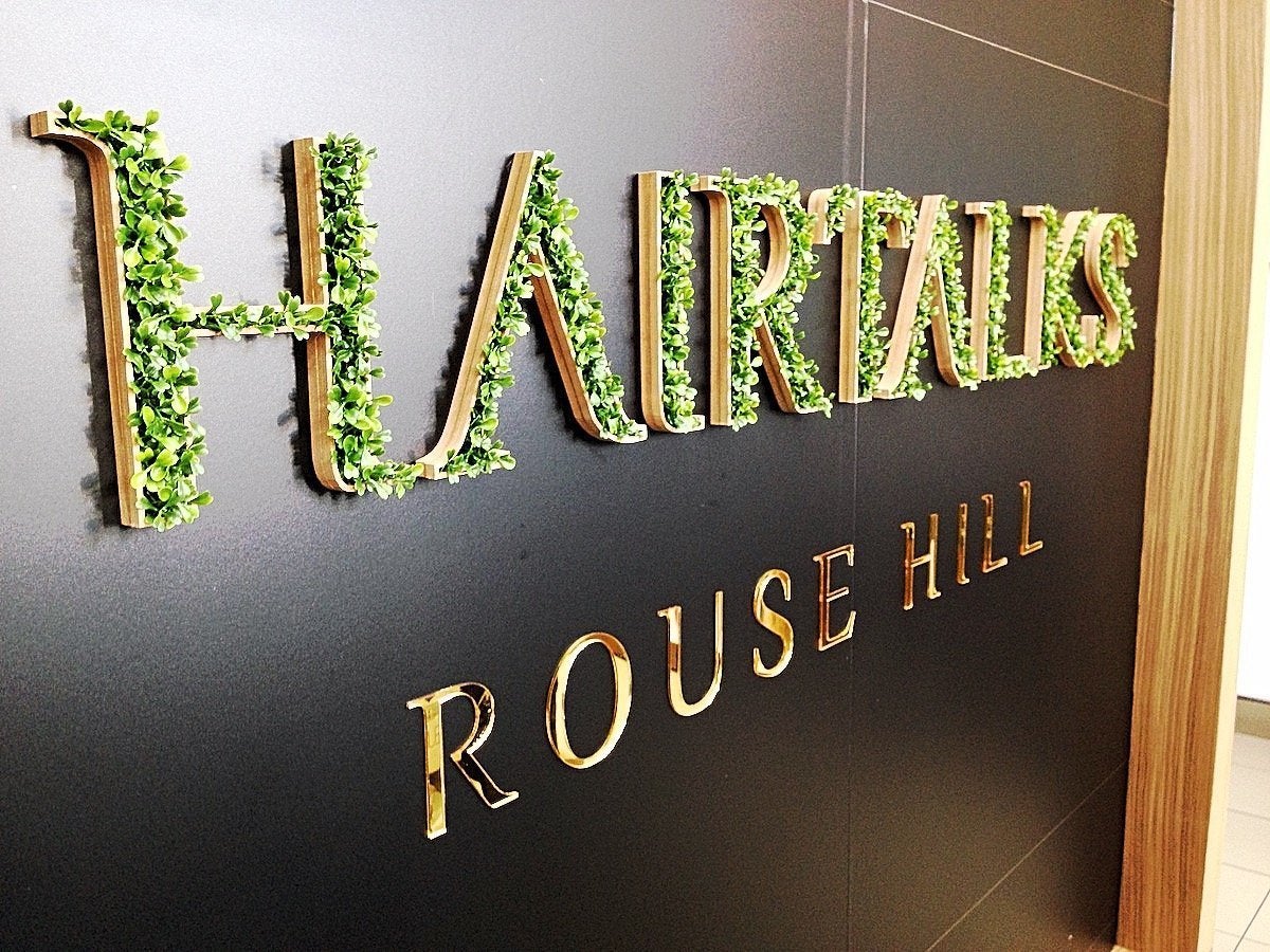 Reception sign for Hairtalks Rouse Hill including fake grass and gold vinyl lettering