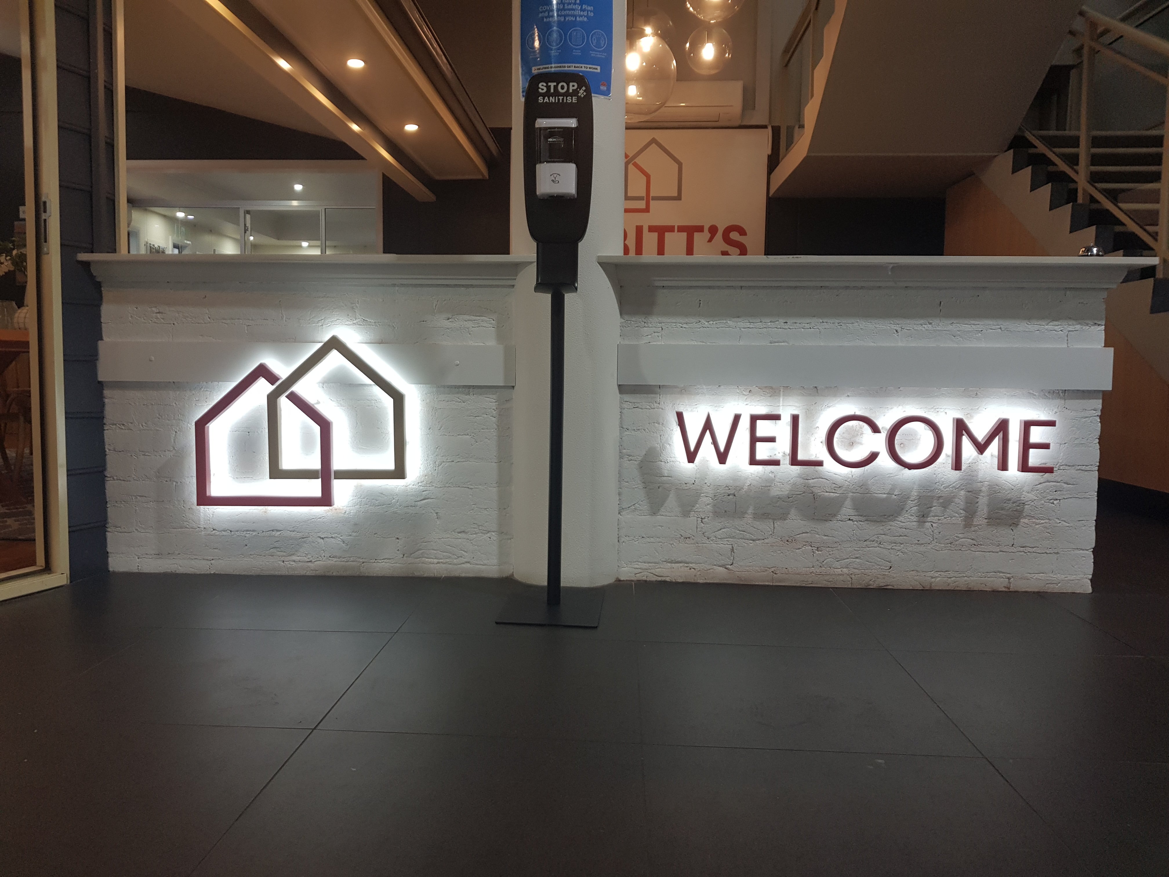 Illuminated 3D Letters on a white brick wall as a business welcome sign