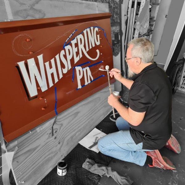 Team member Mick hand painting a tradition sign