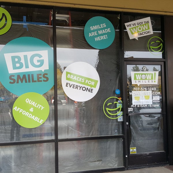 Wow Smiles graphics and colorful circular decals across storefront windows