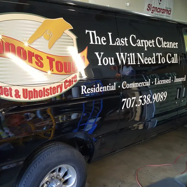 Side view of a black carpet and upholstery service van with a large logo and service lettering