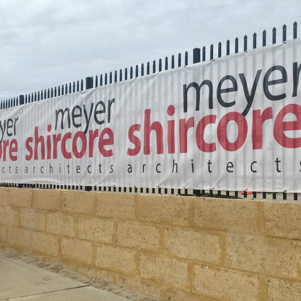 White fence mesh banner with black and red branded text | Temporary Fence Signage