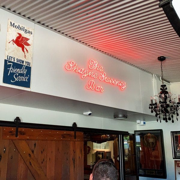 A bright red neon sign above a bar entrance| Neon Signs