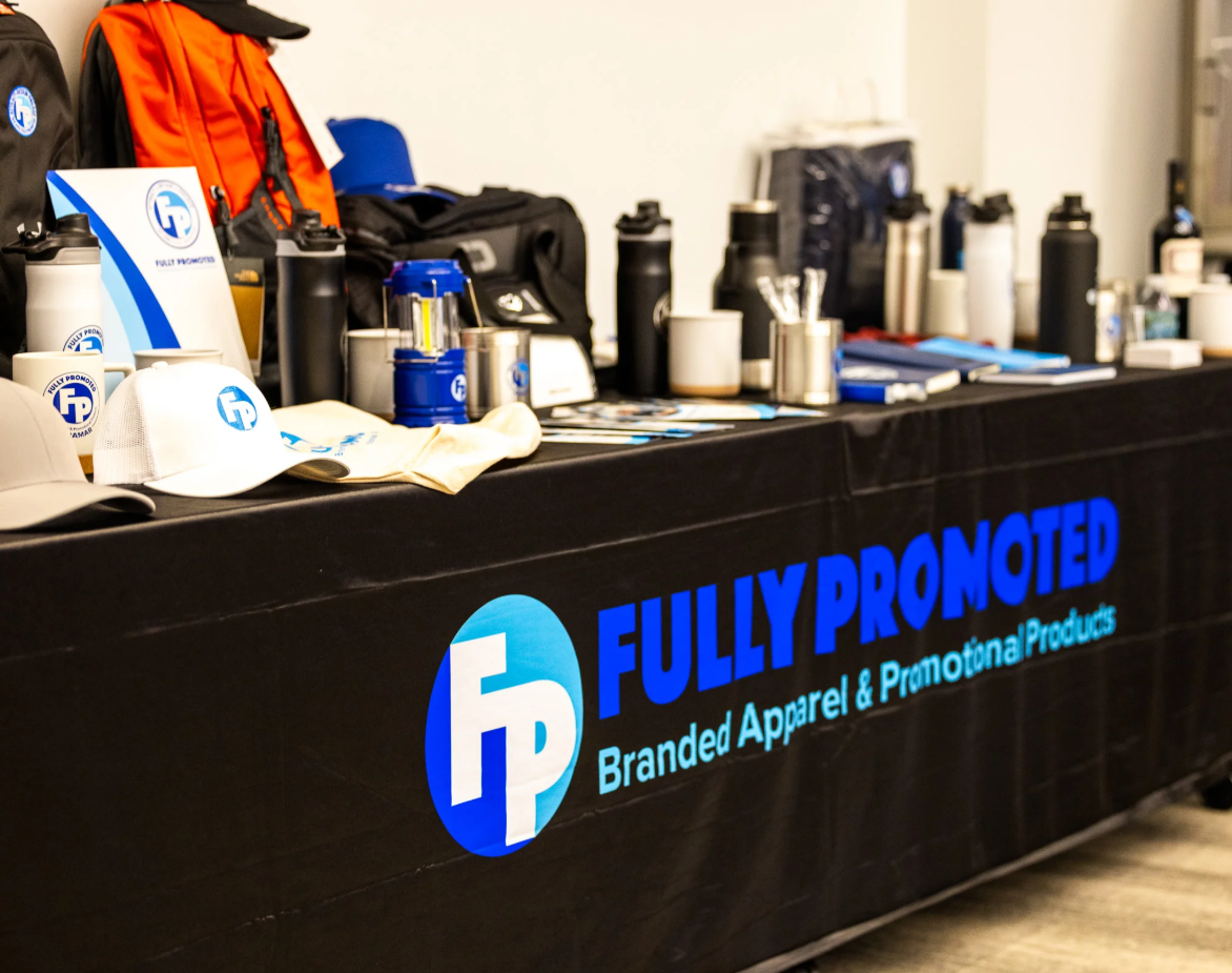 A Fully Promoted Branded conference room table including embroirdered white hats, branded water bottles, pens, and additional items. 