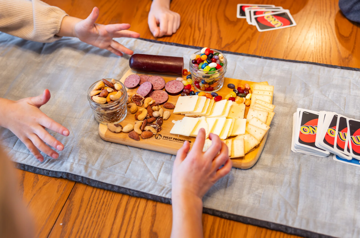 A group of people around a Fully Promoted Branded charcuterie Borard